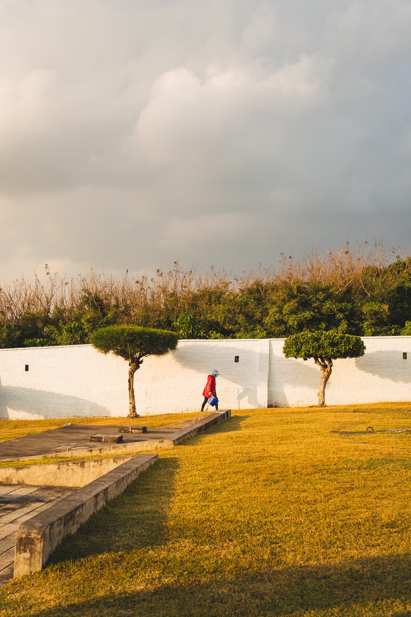 Golden light over a park with white walls and trimmed trees