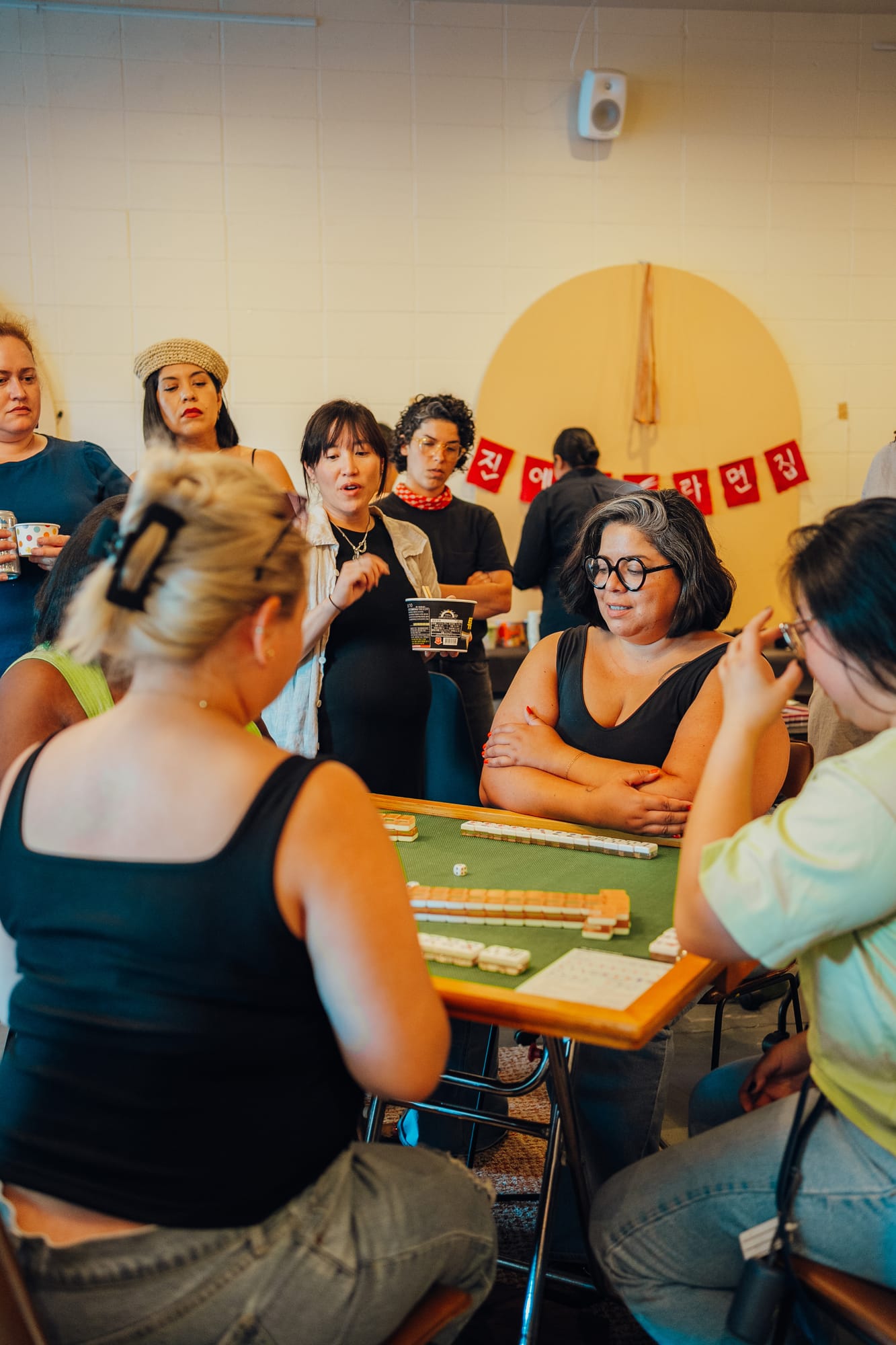 Friends crowded around a mahjong table at a house party