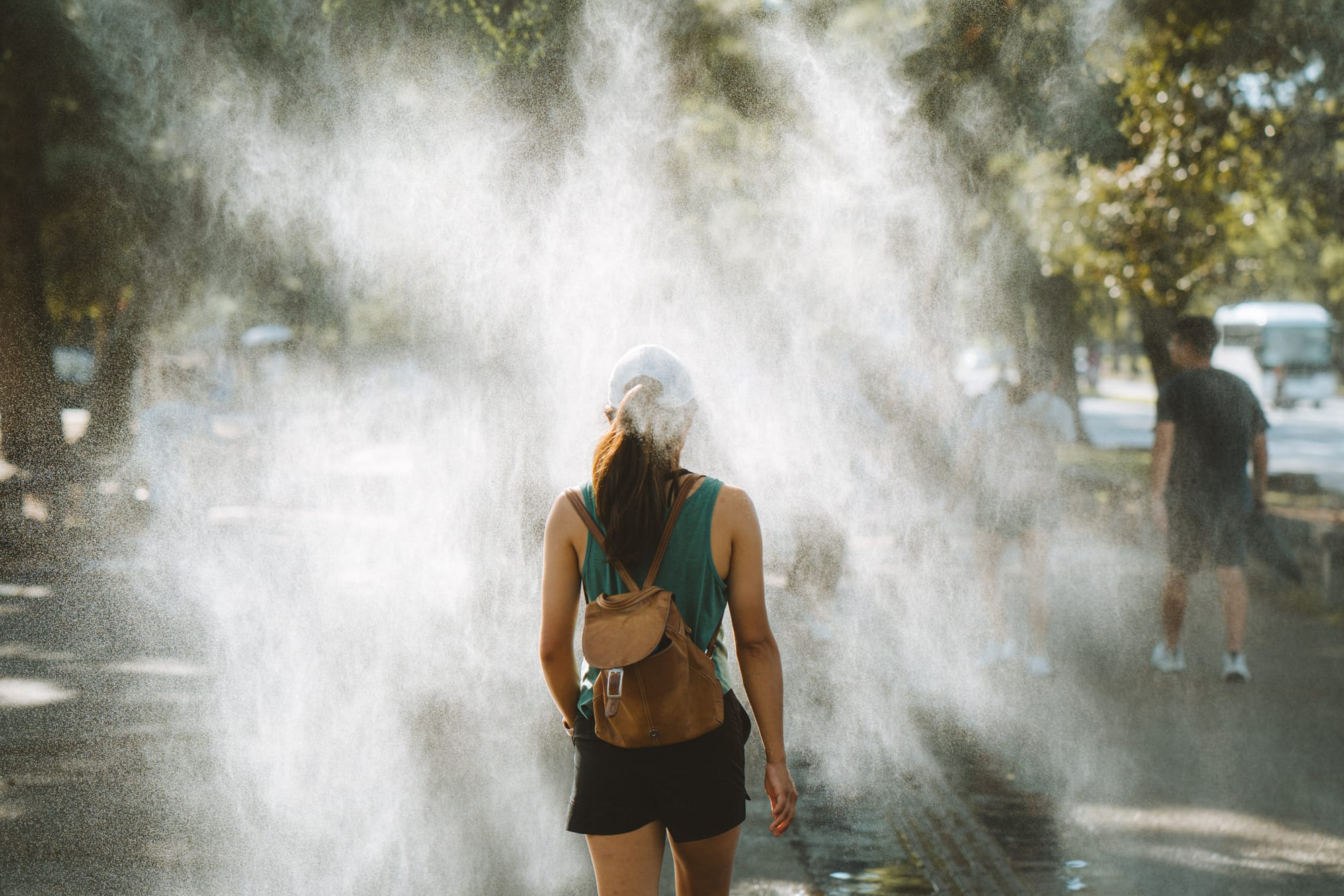 Woman walking through backlit mist on a city street