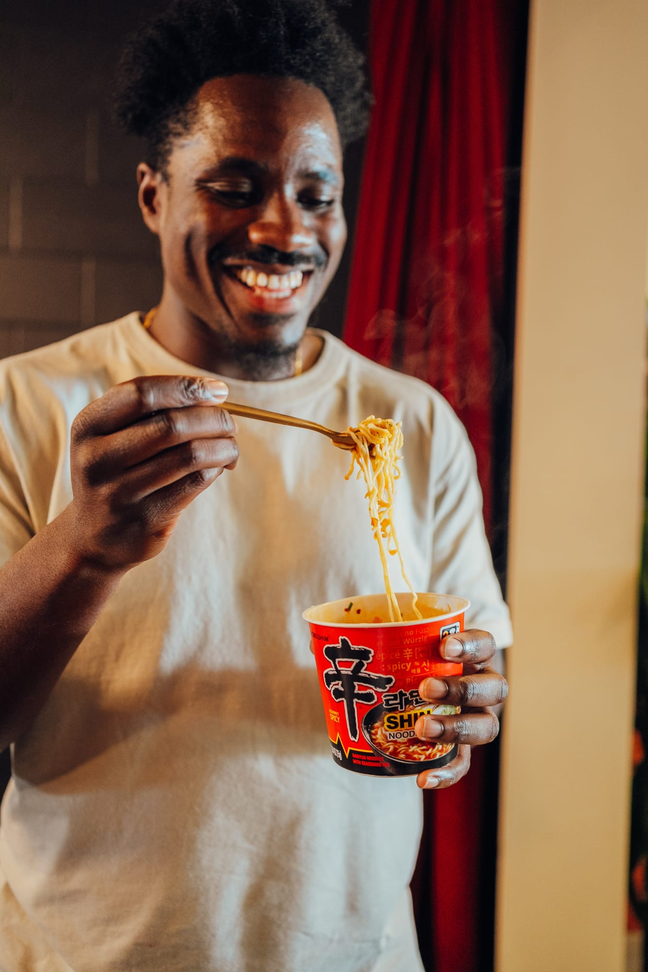 Man grinning over a cup of instant noodles