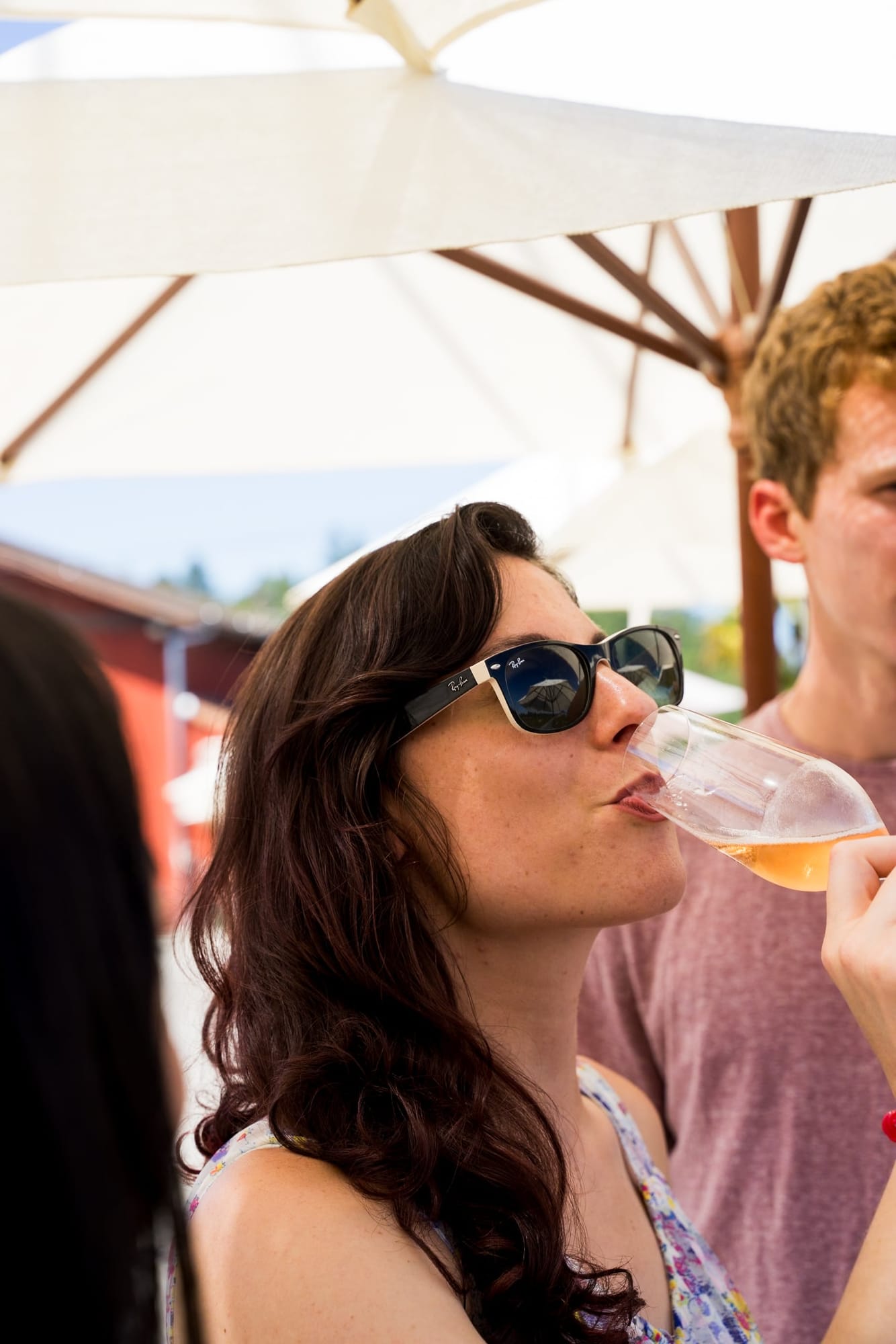 Guest sipping wine under an umbrella at an outdoor party