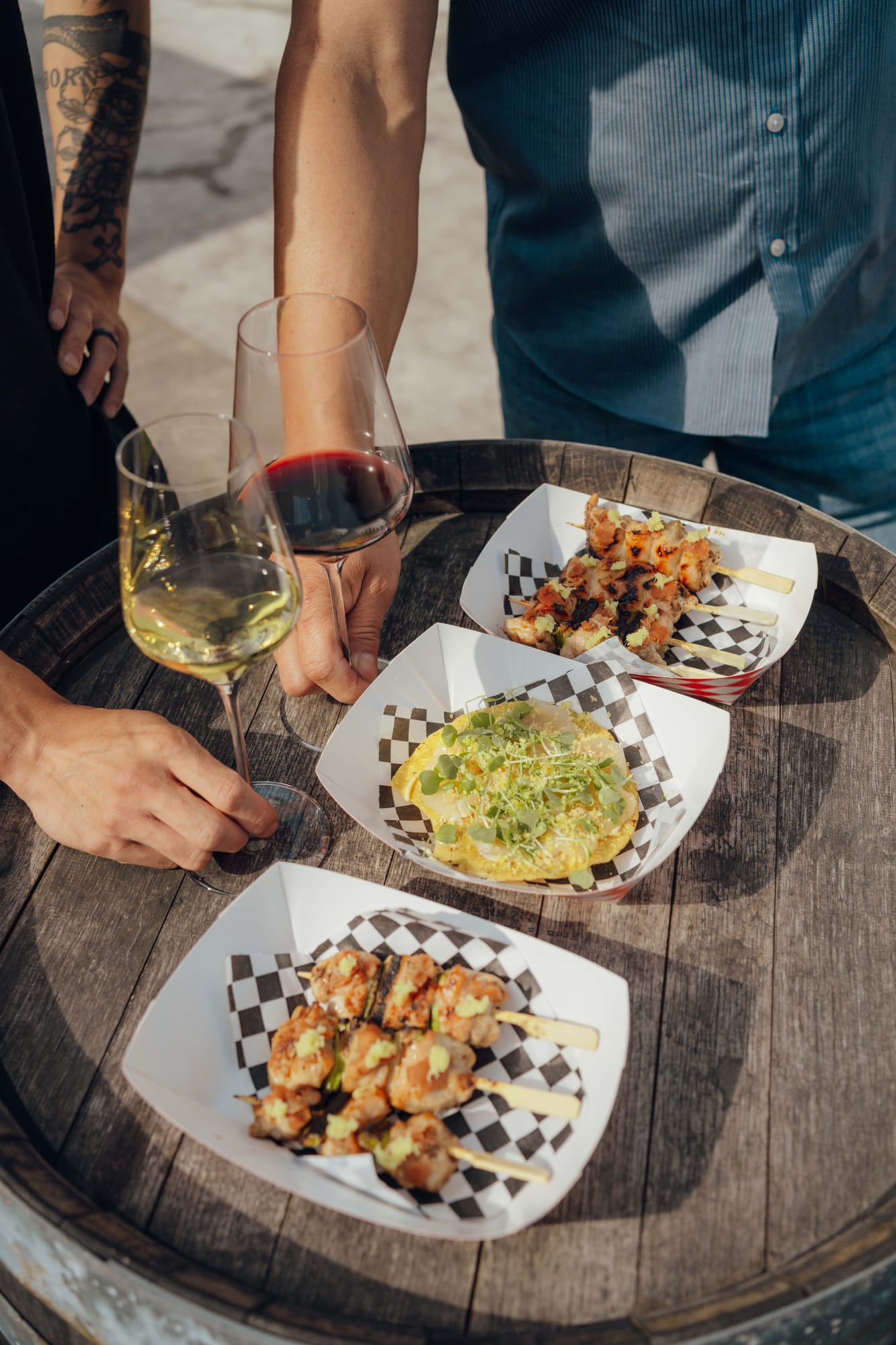Grilled skewers and two glasses of wine on a barrel table