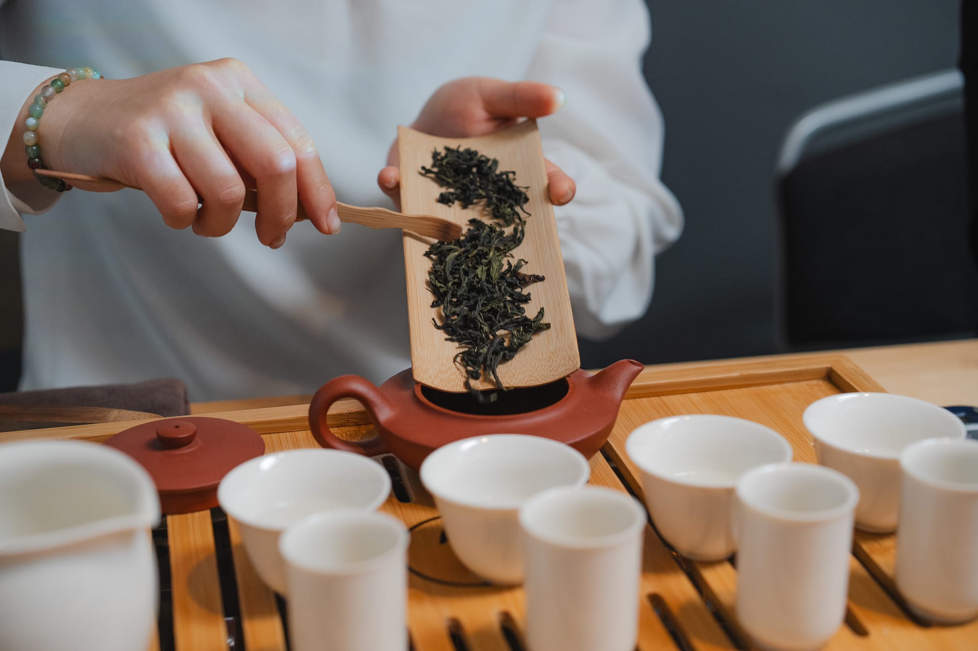 Loose tea being measured over a set of white cups